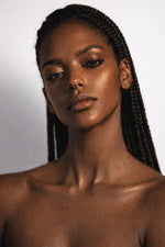 Amber Roulette vegan liquid foundation on Ebony model with long braids by Honor The House