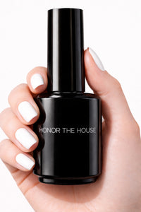 Cloud White vegan nail polish on white model hands holding product bottle by Honor The House