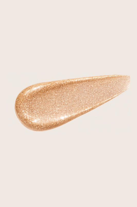 A creamy swatch of Honor the House 02 Honey Soft Glow, a champagne liquid highlighter for dewy skin showing a shimmer-heavy, seamless blend texture for a natural lit-from-within glow.