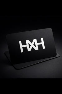 Honor The House Gift Card with HXH badge logo in white on black card with grey/black background. Card leans on a slight angle.