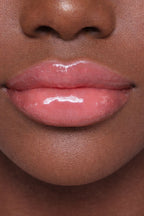Dark model showcasing Honor The House Caribbean Sun SPF 30 Lip Balm in Rum Raspberry flavor.
