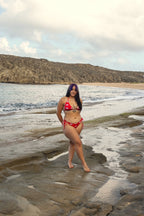 Model wearing Honor The House Breeze Off The Ocean Bikini in Caribbean Cherry colorway in a beach cove.
