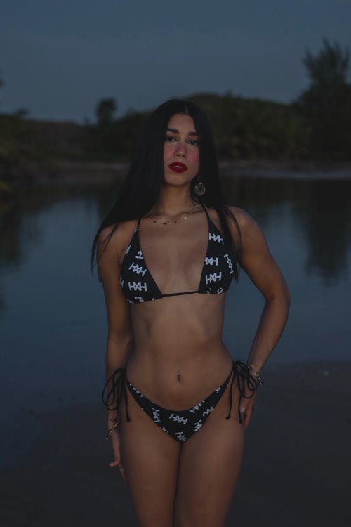 Model wearing Honor The House Breeze Off The Ocean Bikini in Umbreon Black Color at shore during the night